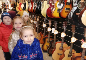 Dzieci stoją przy gitarach w sklepie muzycznym